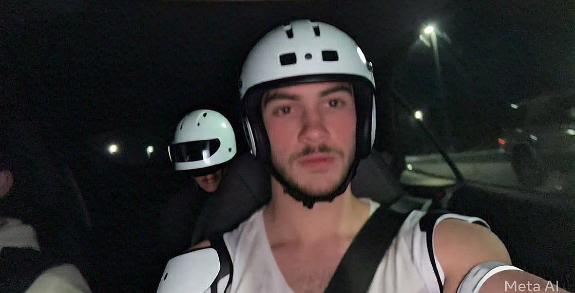 Sruly and a friend wearing white helmets and shoulder pads inside a car at night