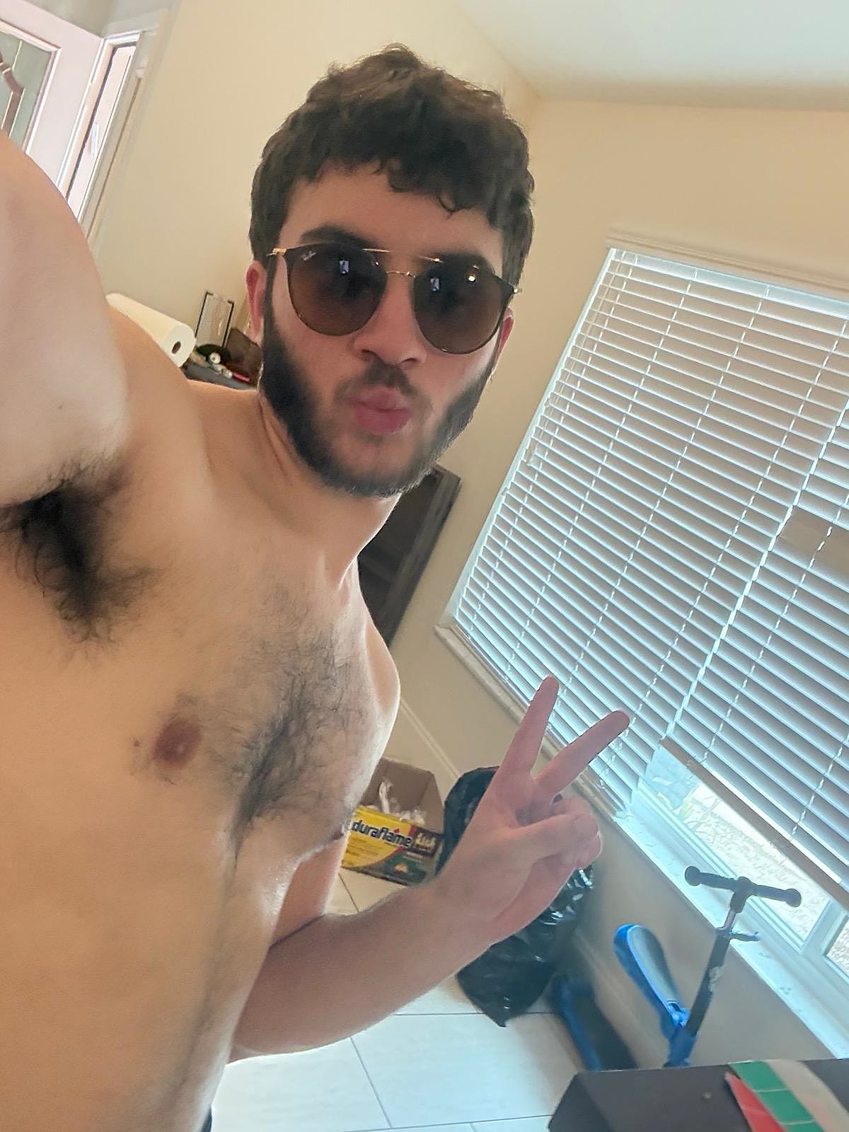 Close selfie of Sruly in sunglasses with a peace sign, armpit prominently in frame