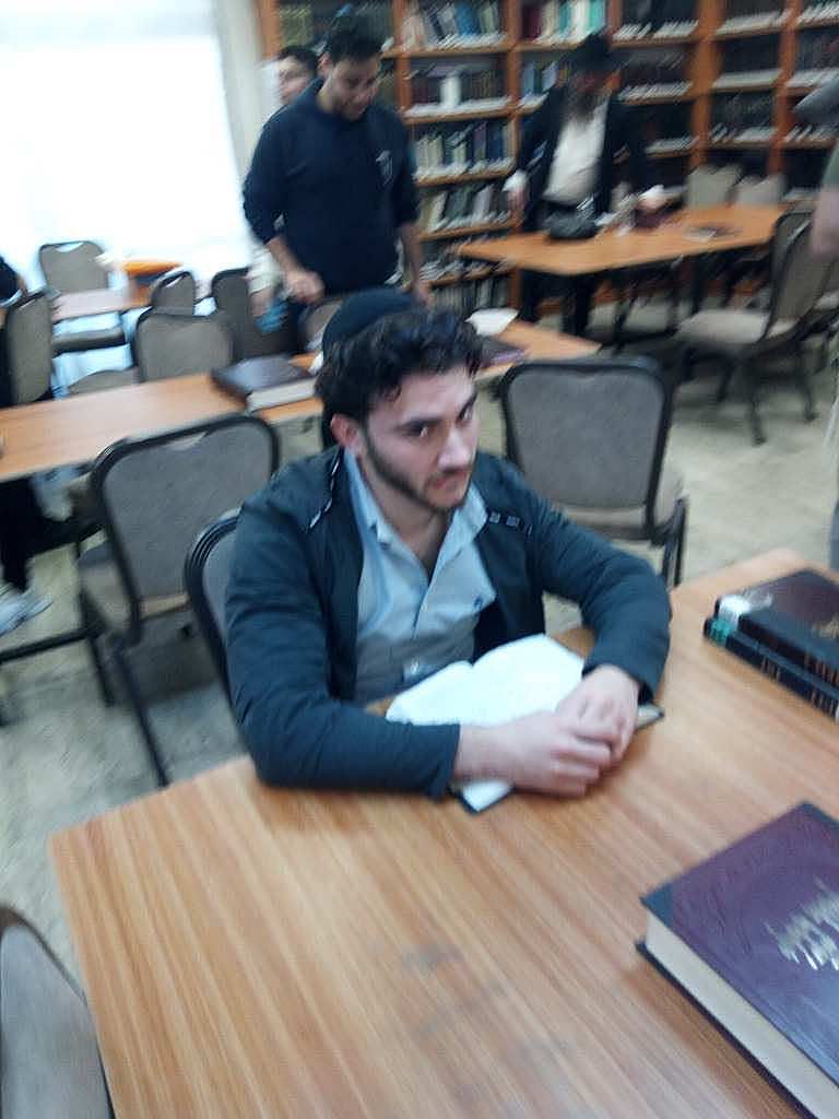 Blurry photo of Sruly at a study table staring directly into the camera