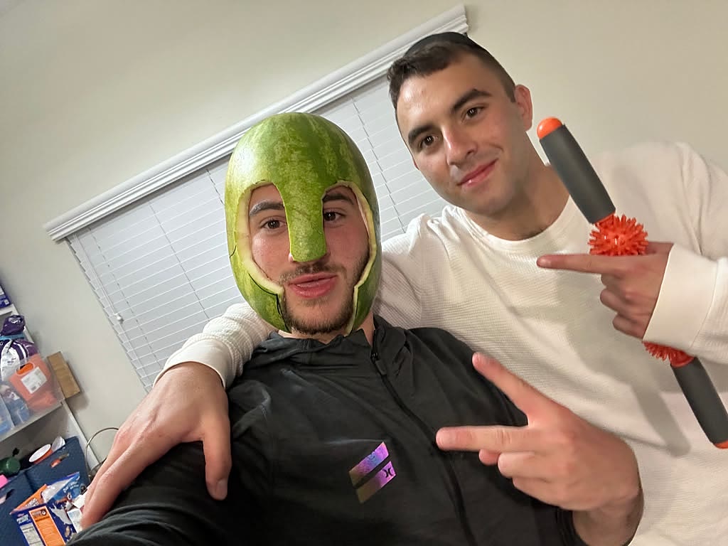 Sruly wearing a hand-carved watermelon as a Spartan helmet, flanked by an accomplice